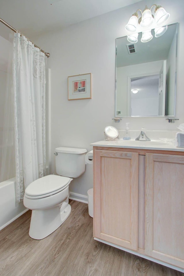 full bathroom featuring visible vents, toilet, an inviting chandelier, wood finished floors, and vanity