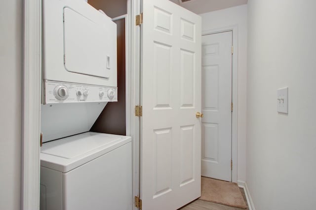 washroom featuring laundry area, stacked washer and clothes dryer, and baseboards