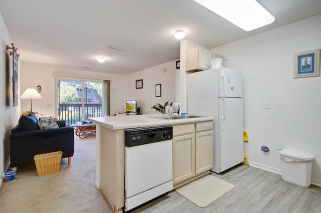 kitchen with a sink, open floor plan, white appliances, a peninsula, and light countertops