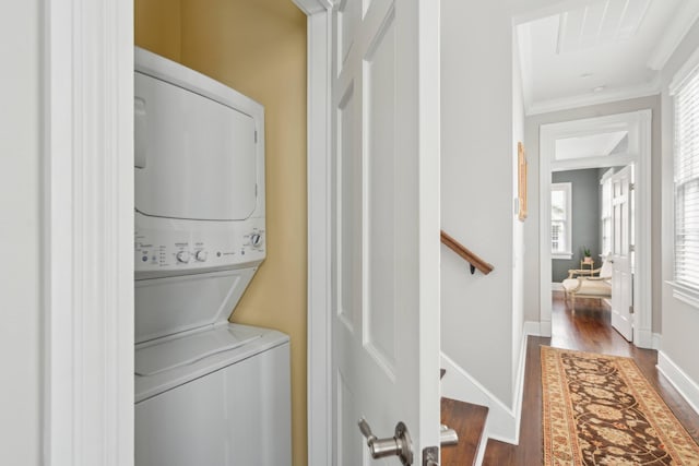 clothes washing area with crown molding, dark wood-type flooring, a wealth of natural light, and stacked washer and dryer