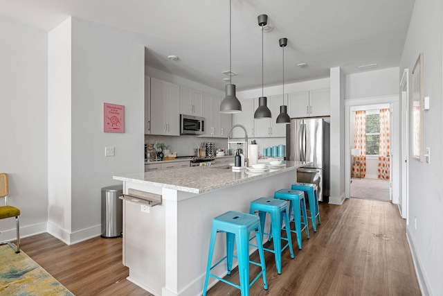 4585 Summey St, North Charleston, SC 29405 - kitchen with appliances with stainless steel finishes, wood finished floors, baseboards, tasteful backsplash, and a breakfast bar