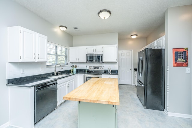 kitchen with backsplash, white cabinetry, a kitchen island, a sink, and black appliances