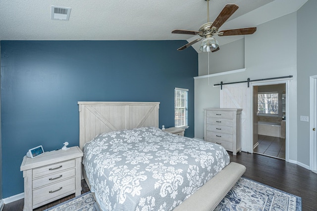 bedroom featuring visible vents, a barn door, dark wood-type flooring, a textured ceiling, and baseboards