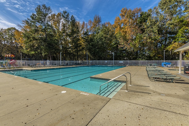 community pool with a patio area and fence