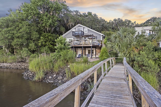 4940 Lambs Rd, North Charleston, SC 29418 - back of property at dusk with brick siding, a deck with water view, and view of wooded area