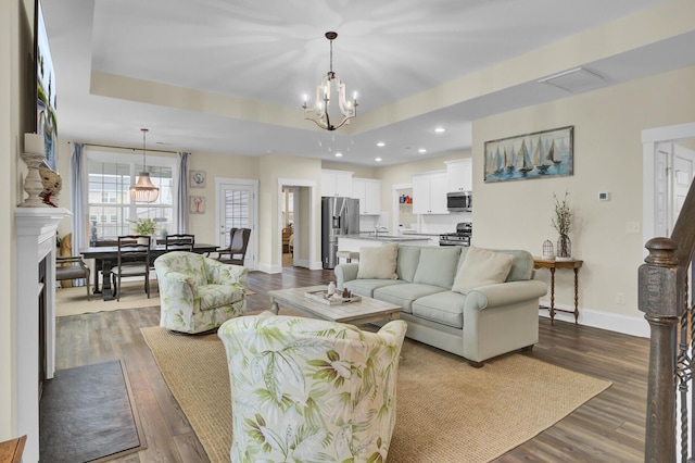 living room featuring dark hardwood / wood-style floors, a tray ceiling, and a chandelier