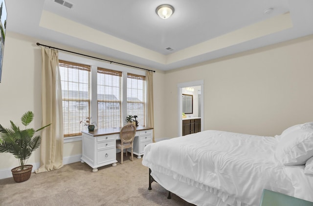 carpeted bedroom with a raised ceiling and ensuite bathroom