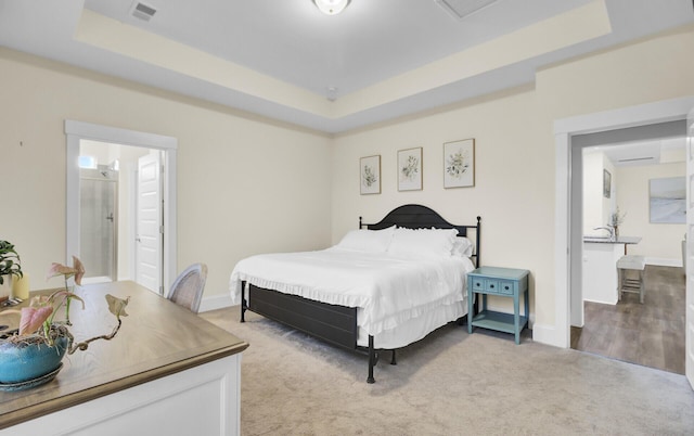 bedroom featuring a tray ceiling and light colored carpet