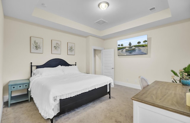 bedroom featuring a tray ceiling and light carpet