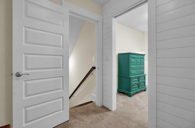 staircase with light colored carpet and wooden walls