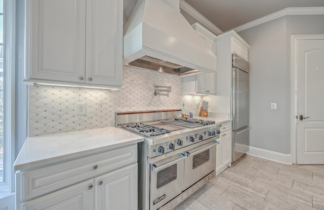 kitchen with premium appliances, crown molding, tasteful backsplash, white cabinetry, and premium range hood