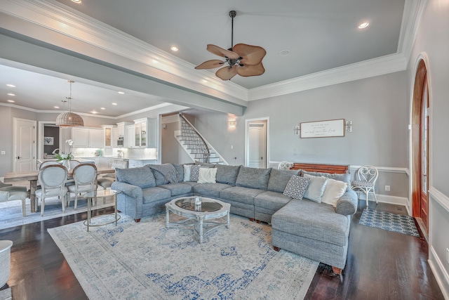 living area featuring crown molding, stairway, and dark wood-type flooring