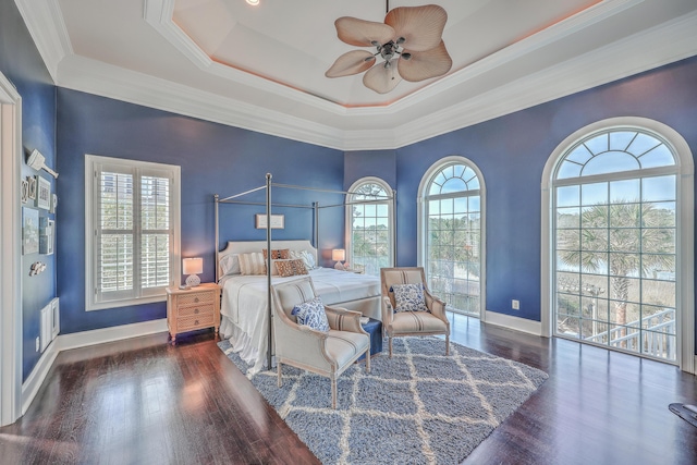 bedroom featuring baseboards, visible vents, a raised ceiling, ornamental molding, and wood finished floors