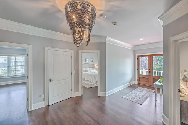 entrance foyer with plenty of natural light, ornamental molding, a chandelier, and dark wood-type flooring