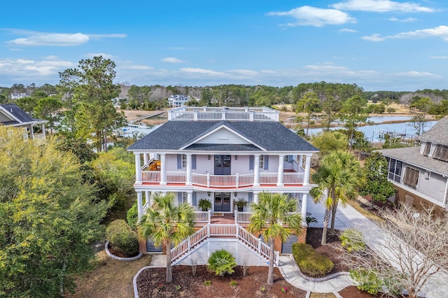 beach home with a water view, a shingled roof, stairway, and a porch