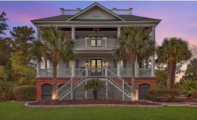 coastal home featuring a balcony, ceiling fan, covered porch, stairs, and brick siding