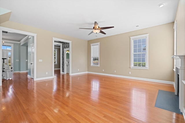 unfurnished living room featuring light wood finished floors, a fireplace with flush hearth, baseboards, and ceiling fan