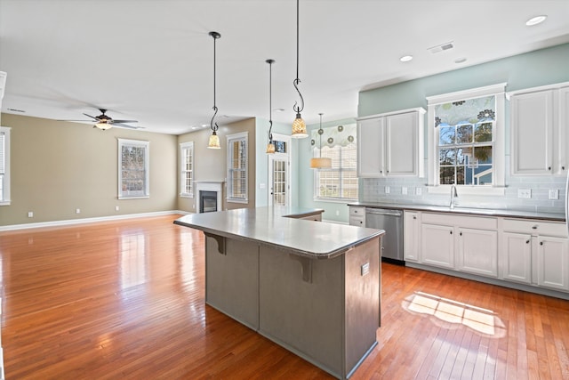 kitchen with tasteful backsplash, visible vents, a glass covered fireplace, a kitchen island, and stainless steel dishwasher