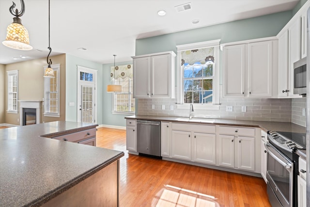 kitchen with dark countertops, visible vents, backsplash, appliances with stainless steel finishes, and a sink