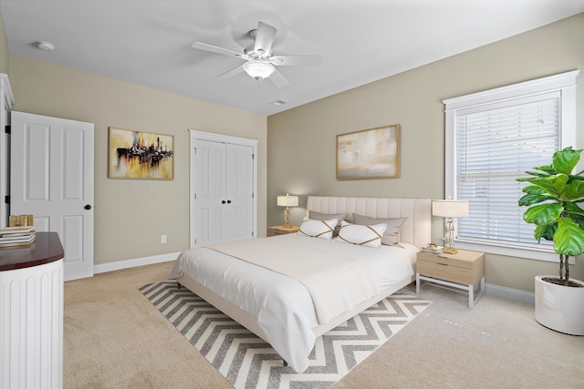 bedroom with light carpet, a closet, baseboards, and a ceiling fan