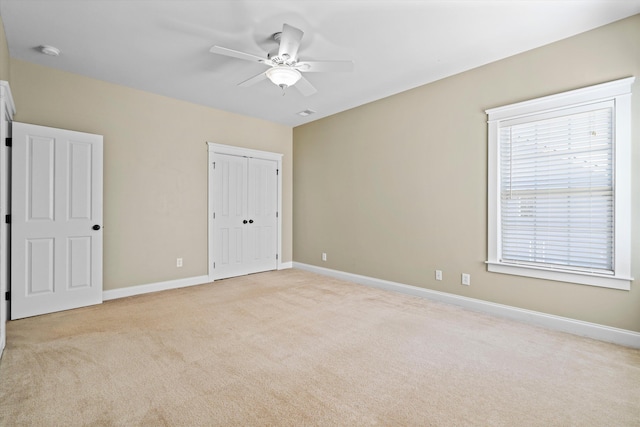 unfurnished bedroom with light carpet, ceiling fan, a closet, and baseboards