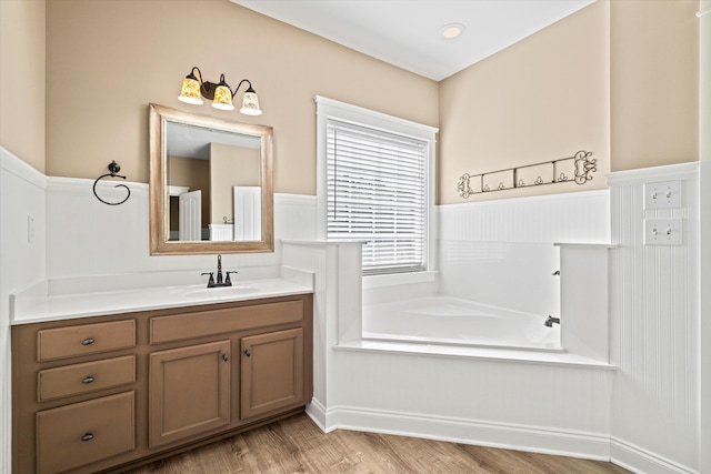 bathroom with a bath, wood finished floors, and vanity