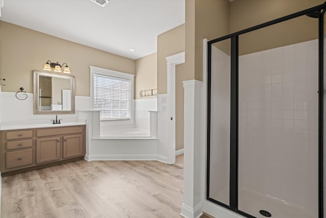 full bathroom featuring visible vents, a shower stall, vanity, wood finished floors, and a bath