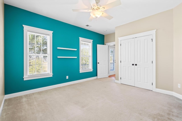 unfurnished bedroom featuring ceiling fan, carpet flooring, visible vents, baseboards, and a closet