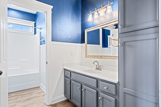 full bath featuring a wainscoted wall, bathing tub / shower combination, wood finished floors, and vanity