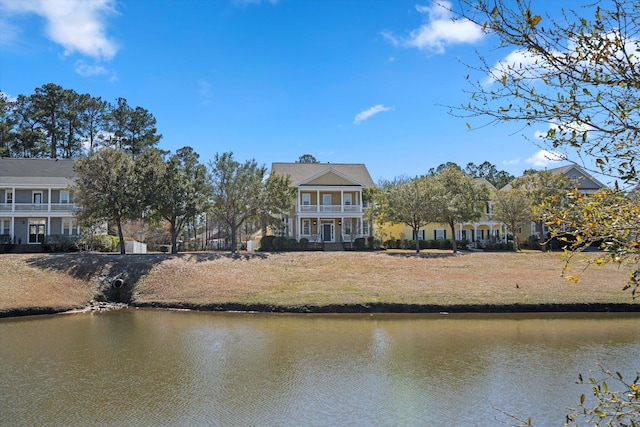 back of house with a water view, driveway, and a balcony