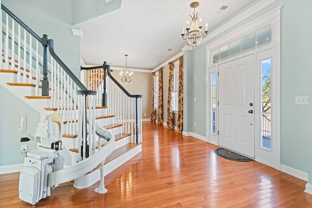 entryway featuring a chandelier, baseboards, stairs, ornamental molding, and hardwood / wood-style floors