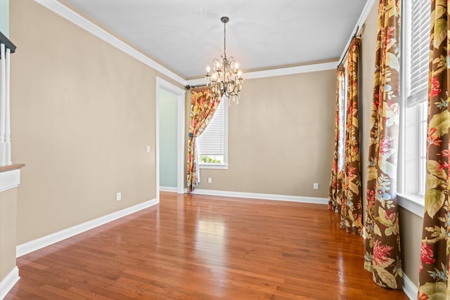 unfurnished room with a chandelier, crown molding, baseboards, and wood finished floors