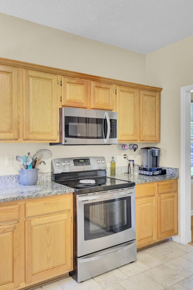 103 Trimley Ct, Goose Creek, SC 29445 - kitchen featuring appliances with stainless steel finishes, light stone counters, a textured ceiling, and light tile patterned flooring