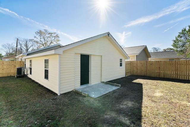 rear view of property with central air condition unit and a yard