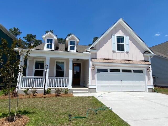 view of front facade featuring an attached garage, concrete driveway, board and batten siding, a front lawn, and a porch