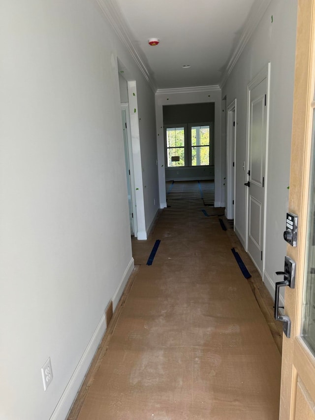 corridor with baseboards and crown molding