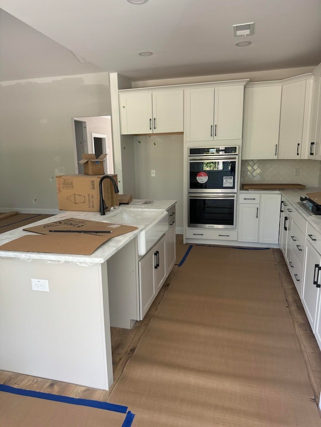 kitchen with visible vents, white cabinets, stainless steel appliances, light wood-style floors, and a sink