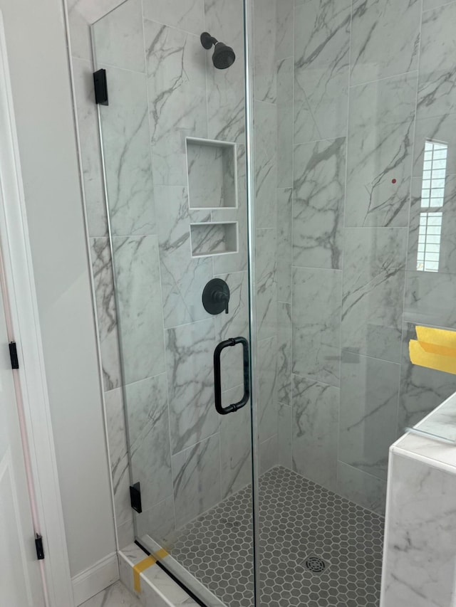 bathroom with marble finish floor and a shower stall