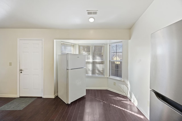 kitchen featuring dark wood-type flooring, stainless steel fridge, and white fridge