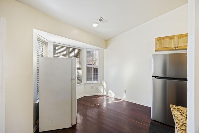 kitchen with dark wood-type flooring, light brown cabinets, white fridge, stainless steel refrigerator, and light stone counters