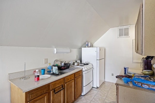 kitchen featuring white appliances, light tile patterned floors, and vaulted ceiling