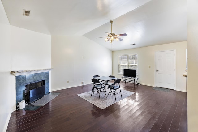 dining room with vaulted ceiling, ceiling fan, dark hardwood / wood-style flooring, and a tile fireplace