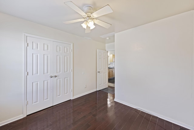 unfurnished bedroom with ceiling fan, dark wood-type flooring, and a closet