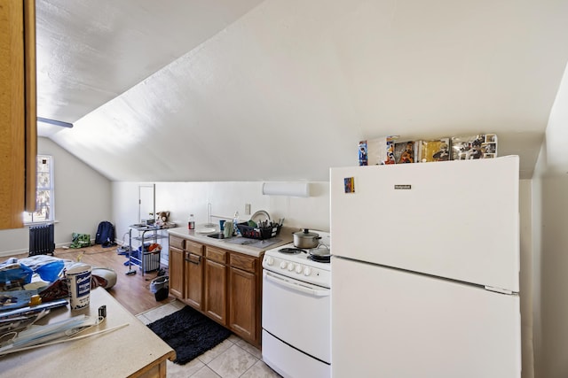 kitchen featuring vaulted ceiling, light tile patterned flooring, and white appliances