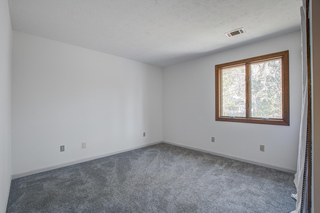 empty room with carpet, visible vents, a textured ceiling, and baseboards