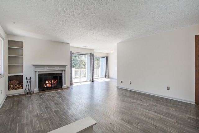 unfurnished living room featuring a textured ceiling, dark wood-type flooring, a fireplace with flush hearth, and baseboards