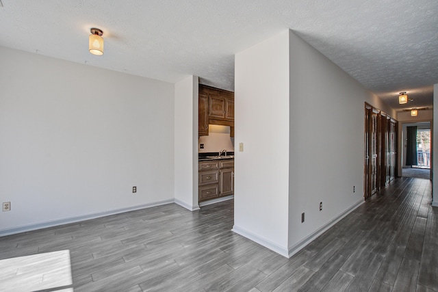 spare room featuring a textured ceiling, a sink, wood finished floors, and baseboards