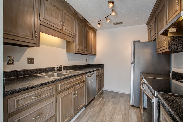 kitchen with under cabinet range hood, stainless steel appliances, a sink, visible vents, and dark countertops