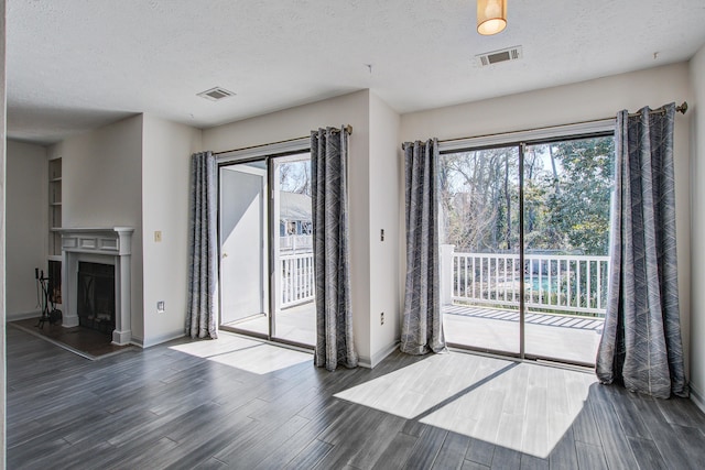 entryway featuring visible vents, a fireplace with raised hearth, a textured ceiling, and wood finished floors