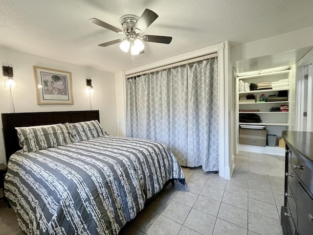 bedroom with a textured ceiling, ceiling fan, and tile patterned floors